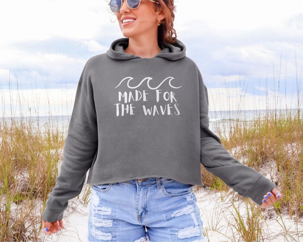Woman wearing a hoodie with 'Made for the Waves' text on a beach